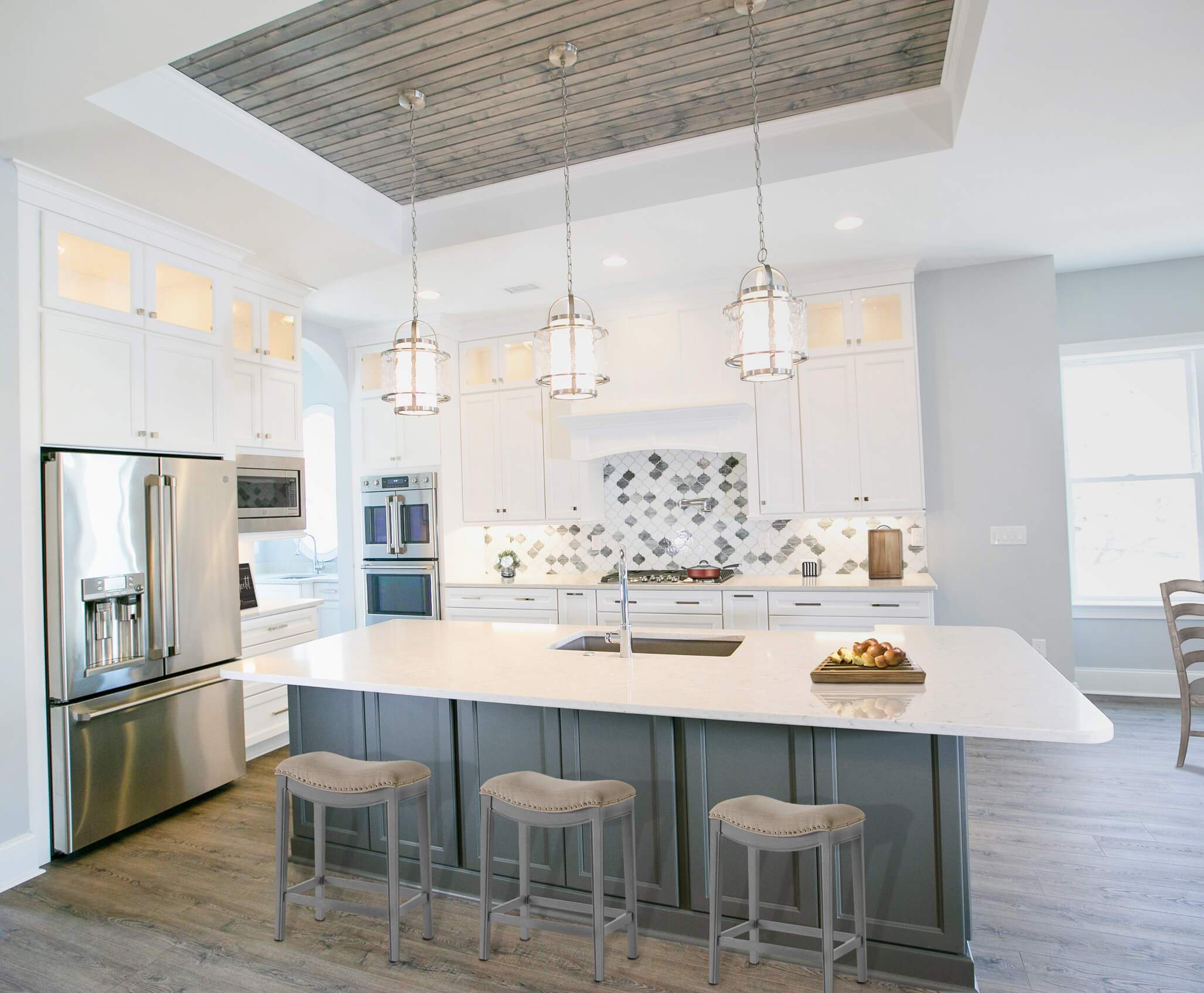 white kitchen with hanging lighting and a light grey center island
