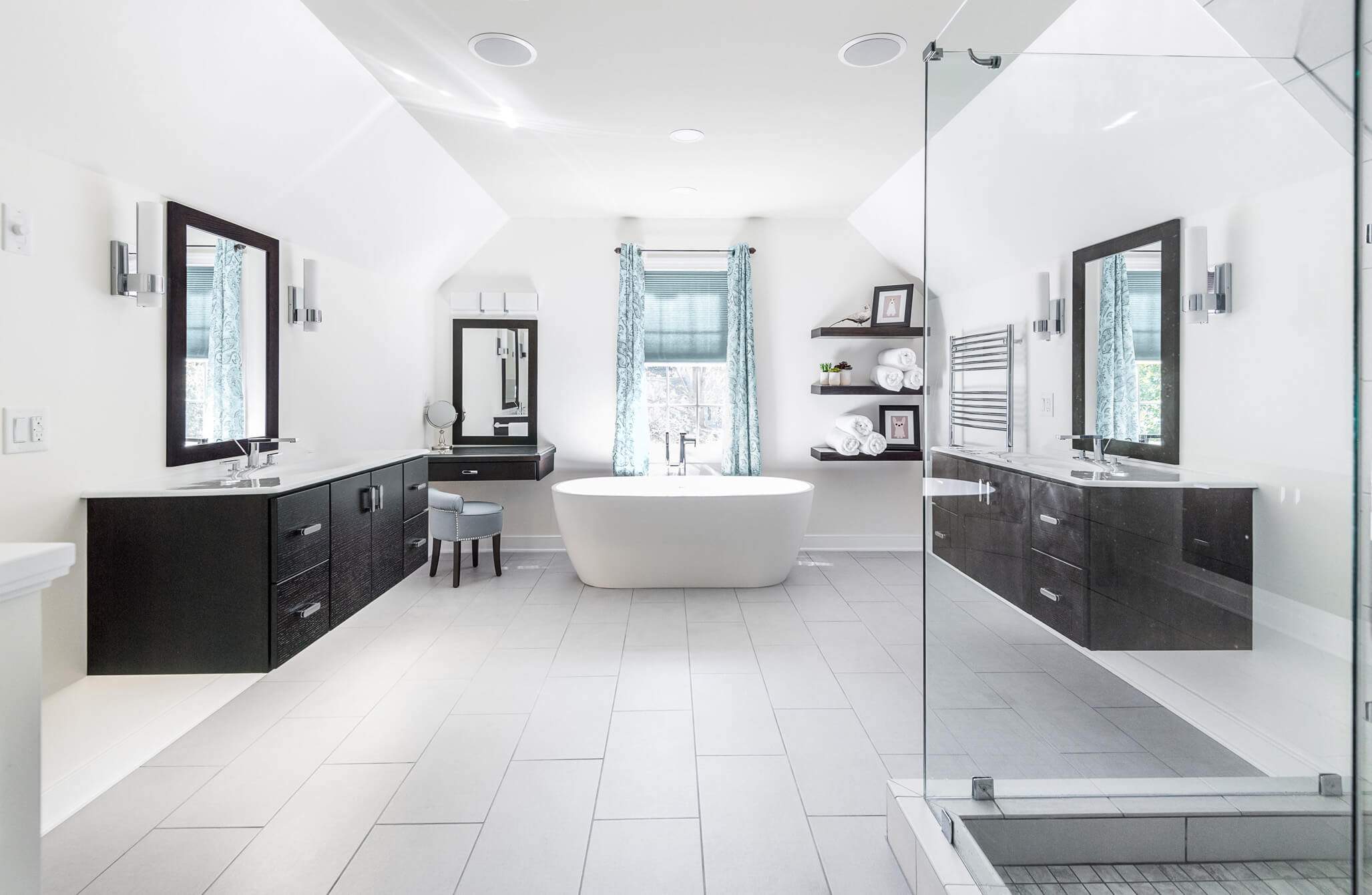 white bathroom with open glass shower and dual dark floating vanities