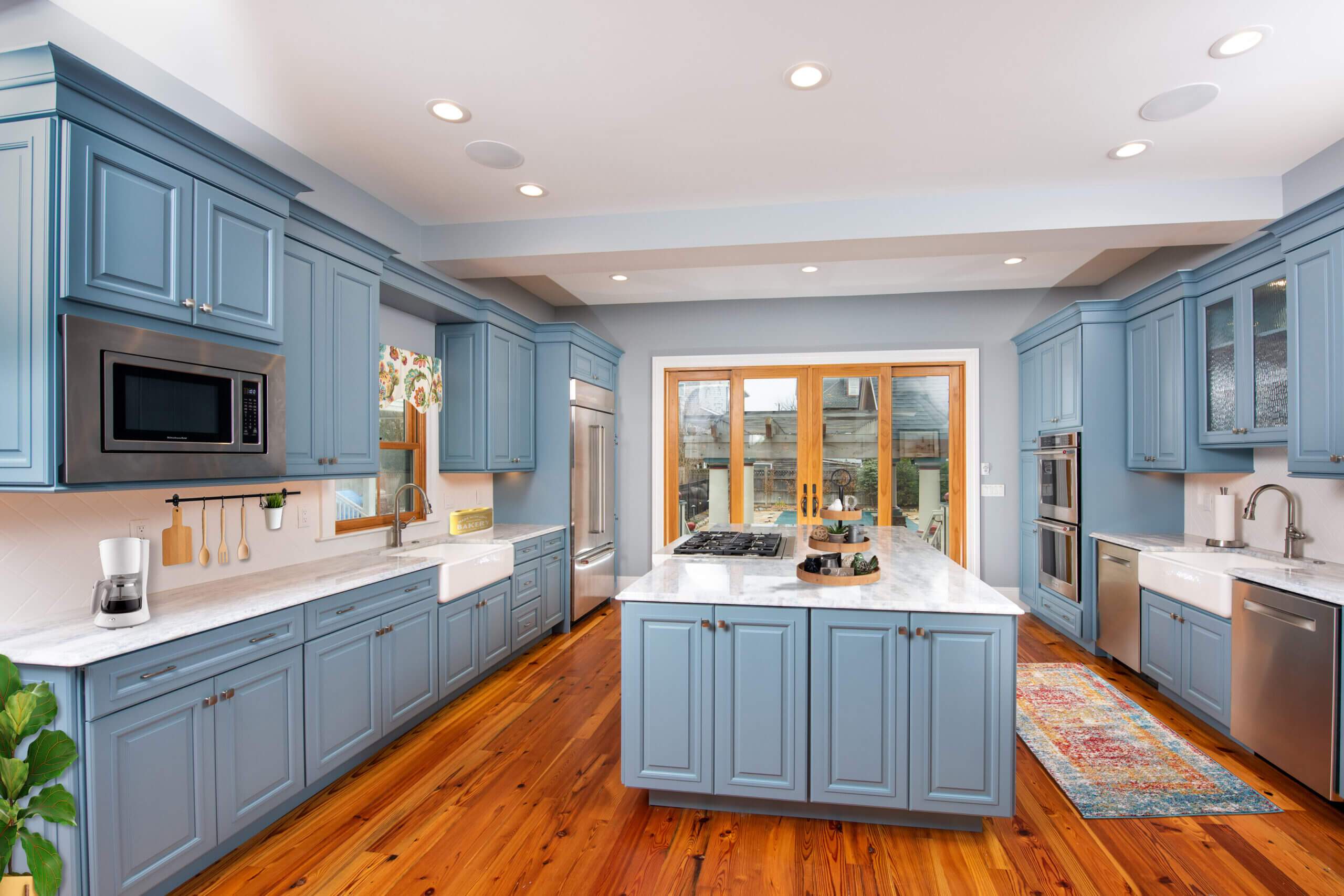 light blue kitchen with hardwood floors and a large center island with stovetop